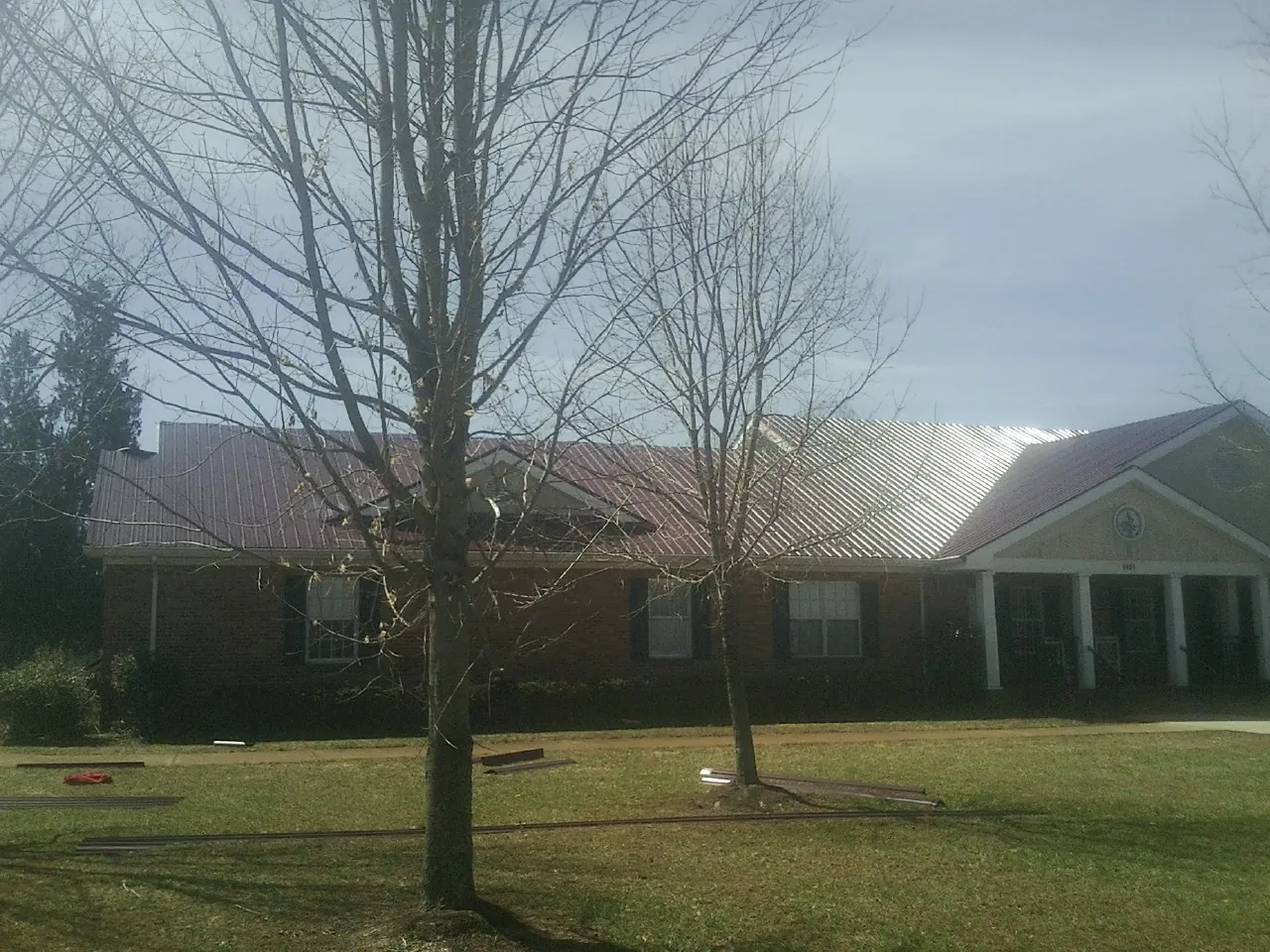 Red metal roof on a brick building seen from the front lawn in New Hyde Park