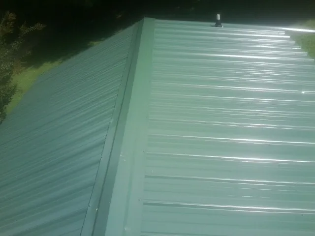 New green metal panels meeting at the ridge of a roof — Flat Roof Repair work by our crew in New Hyde Park