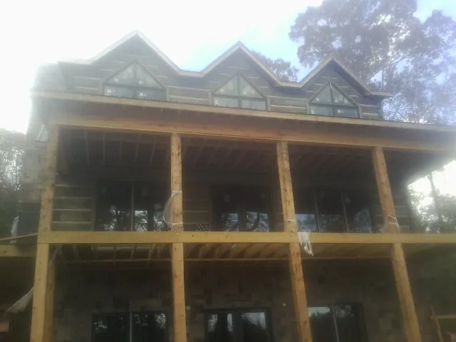 Dormers and porch framing on a large log home under construction — Roof Coating work by our crew in New Hyde Park