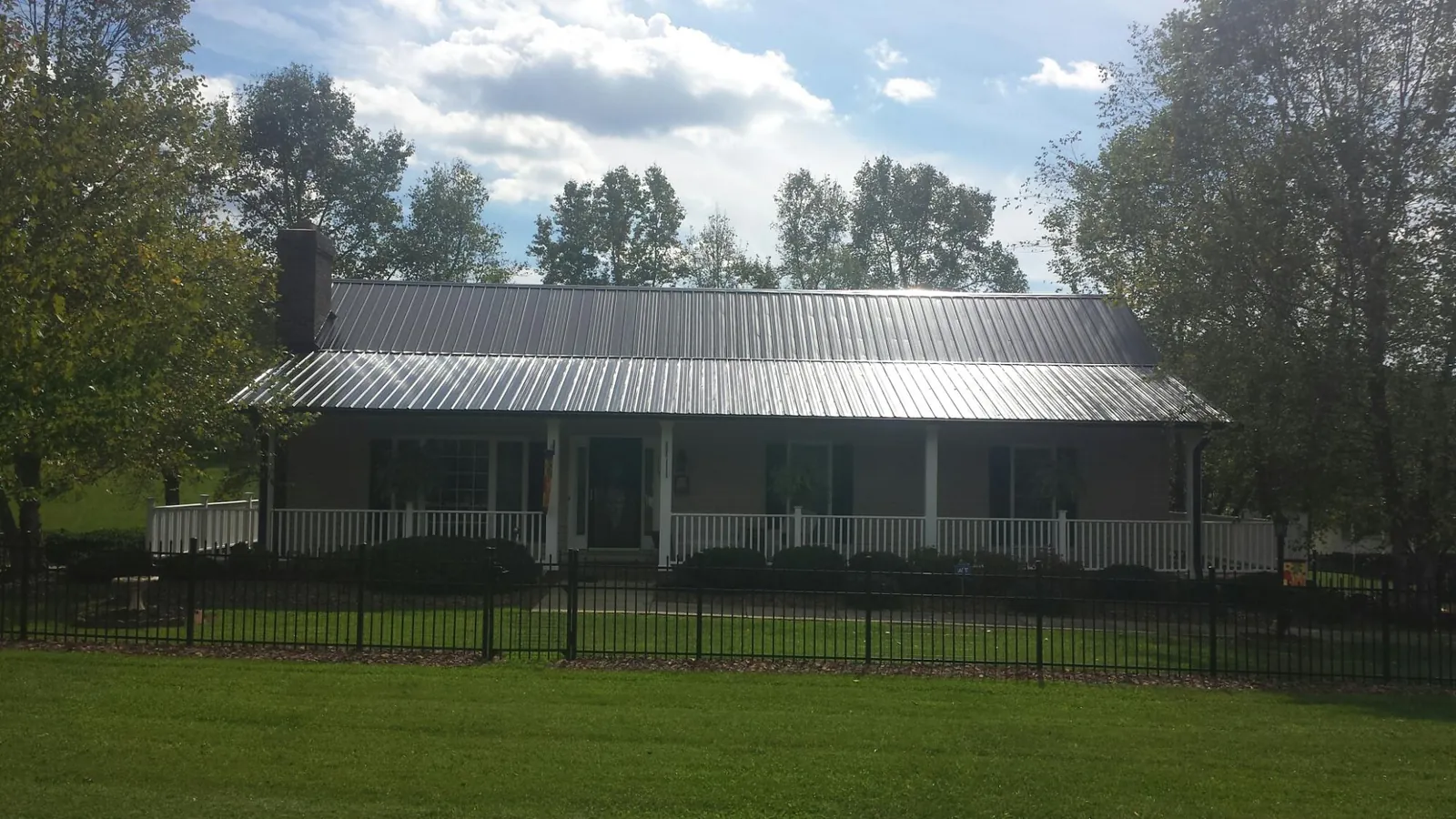 Gray metal roof on a brick ranch with a full width front porch — Gutter Guard Installation work by our crew in New Hyde Park