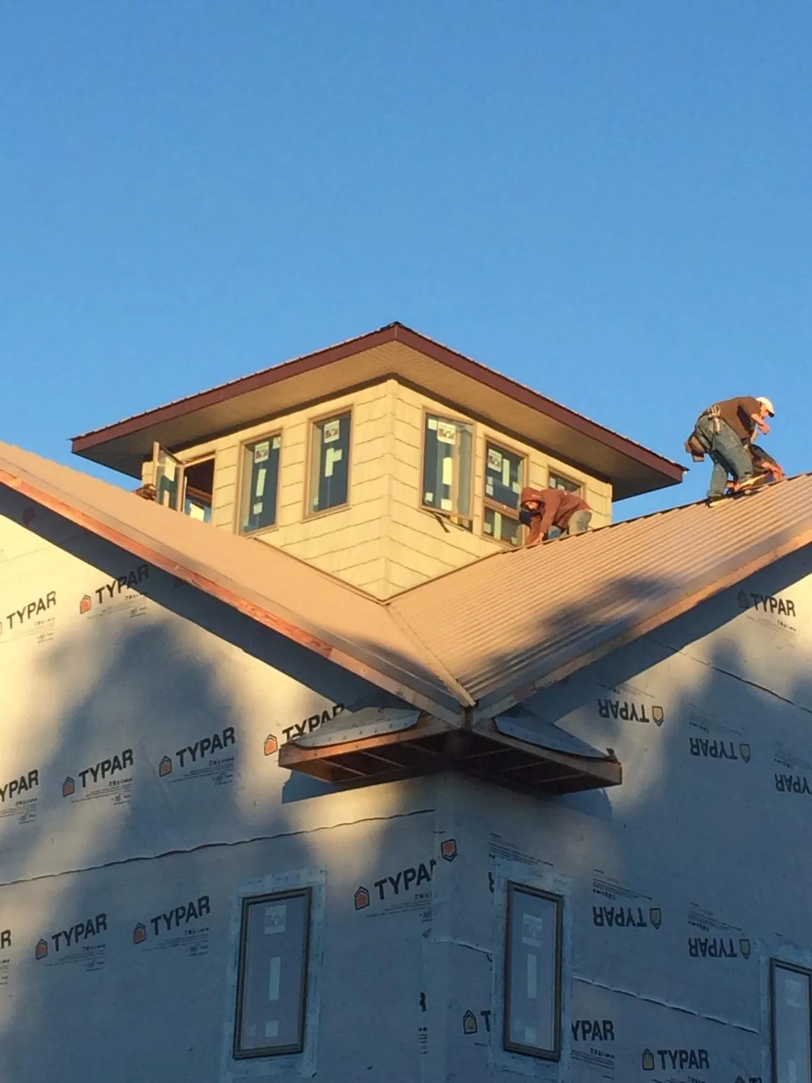 Roofers working around a rooftop cupola on a new metal roof at sunset — Roof Waterproofing in New Hyde Park by Roofing Brothers